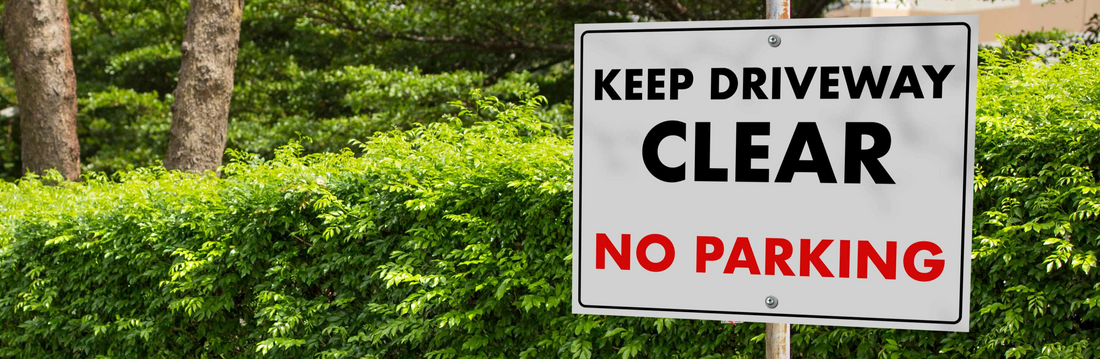 Keep Driveway lear No Parking Sign in front of hedge